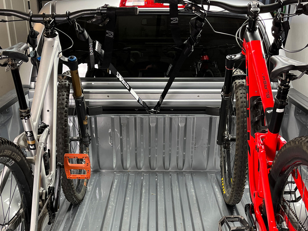 Two mountain bikes tied down to the Hybrid Moto Rack in the back of a truck.