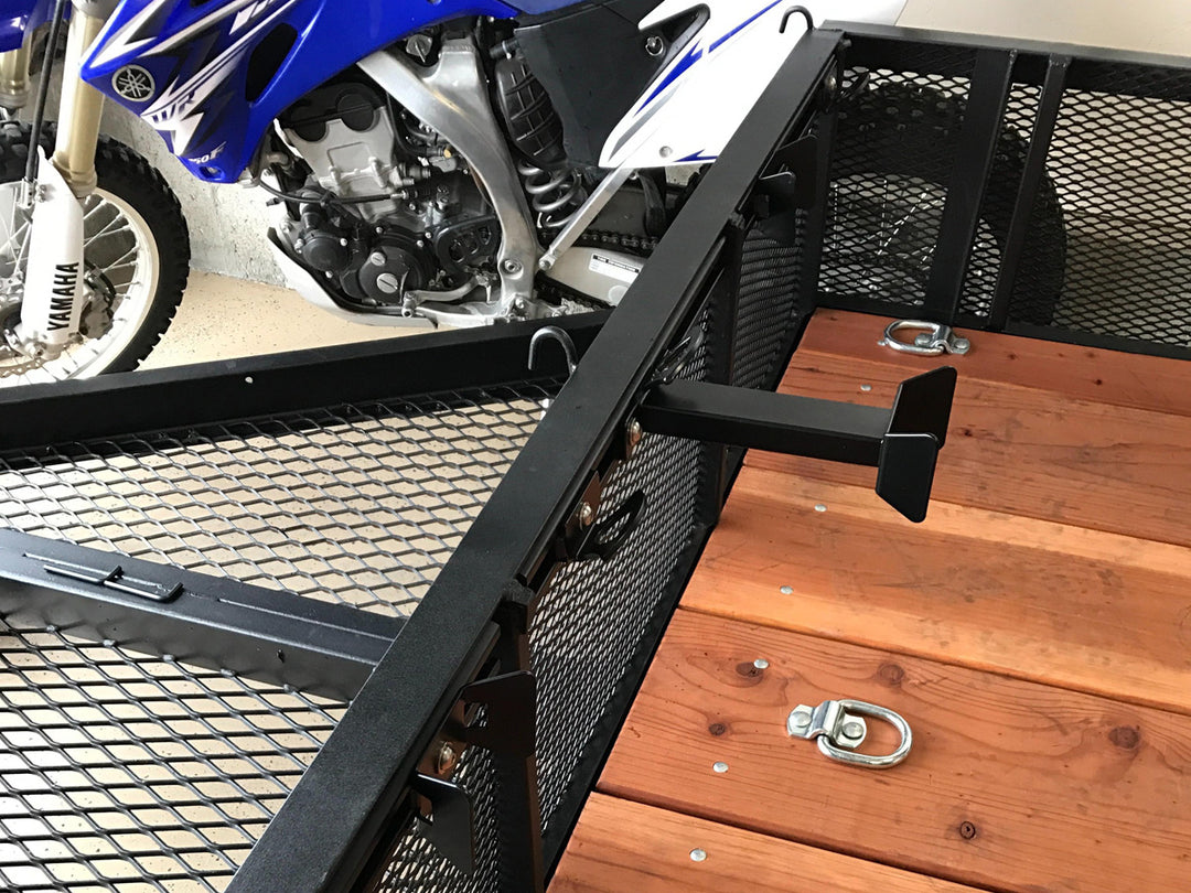 A utility trailer with a CCR Sport moto rack mounted to the front of the trailer with an offset wheel chock.