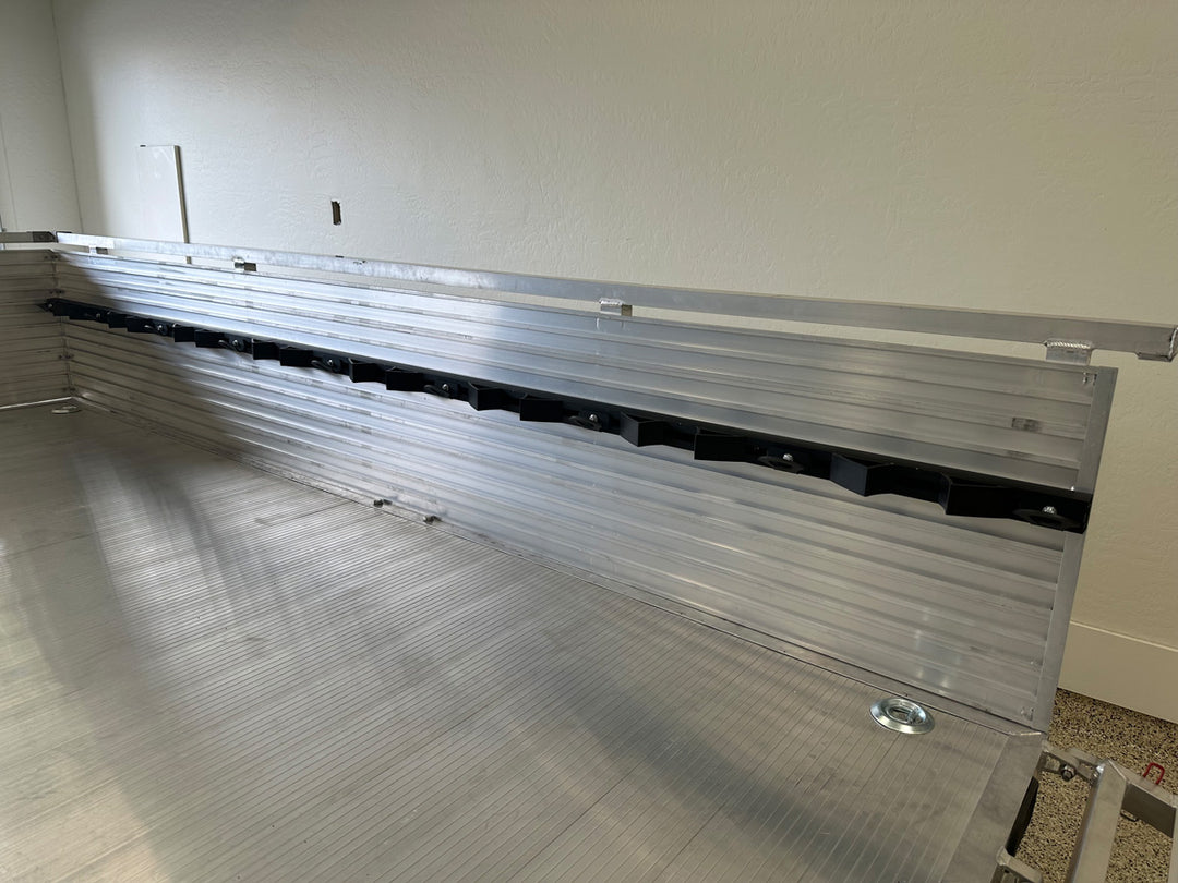 An aluminum utility trailer shown with the Hybrid Moto Rack System mounted to side wall of the trailer.