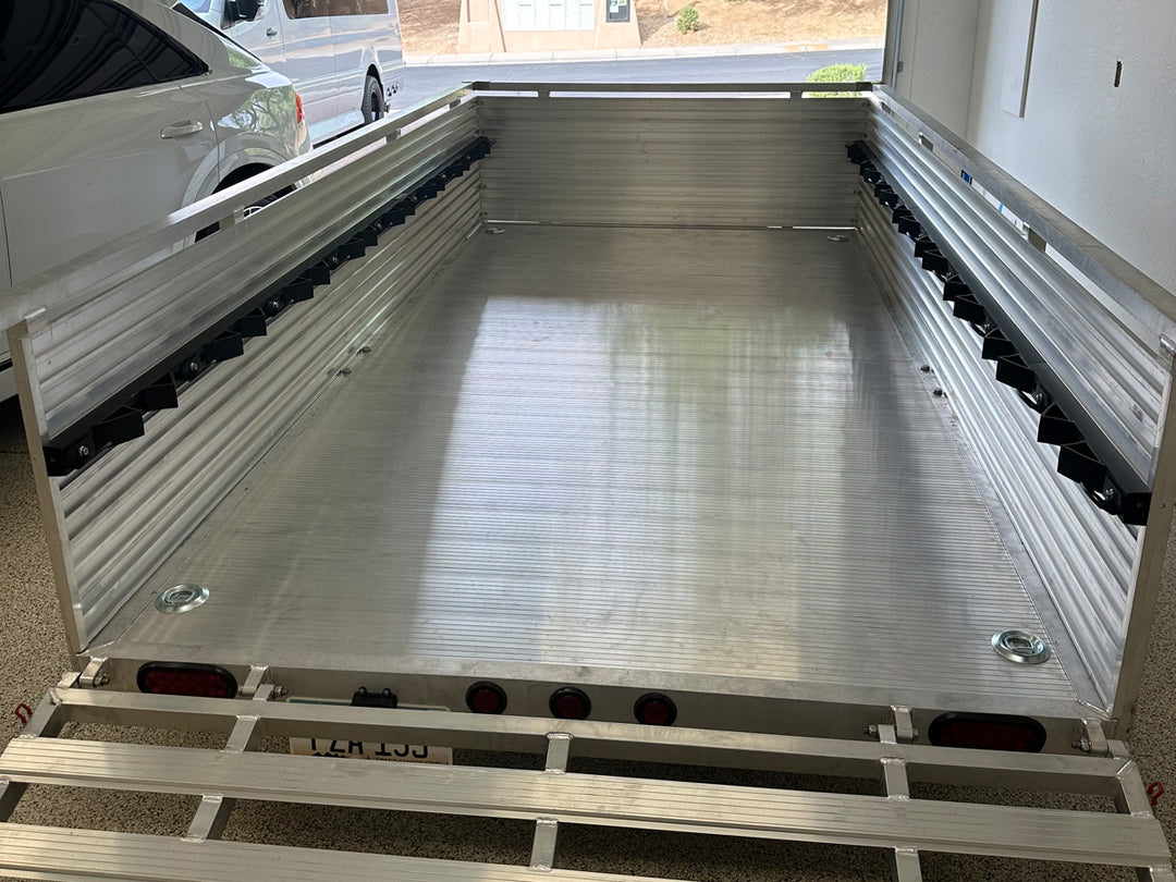 A clean image of an aluminum utility trailer outfitted with the Hybrid Moto Rack system.
