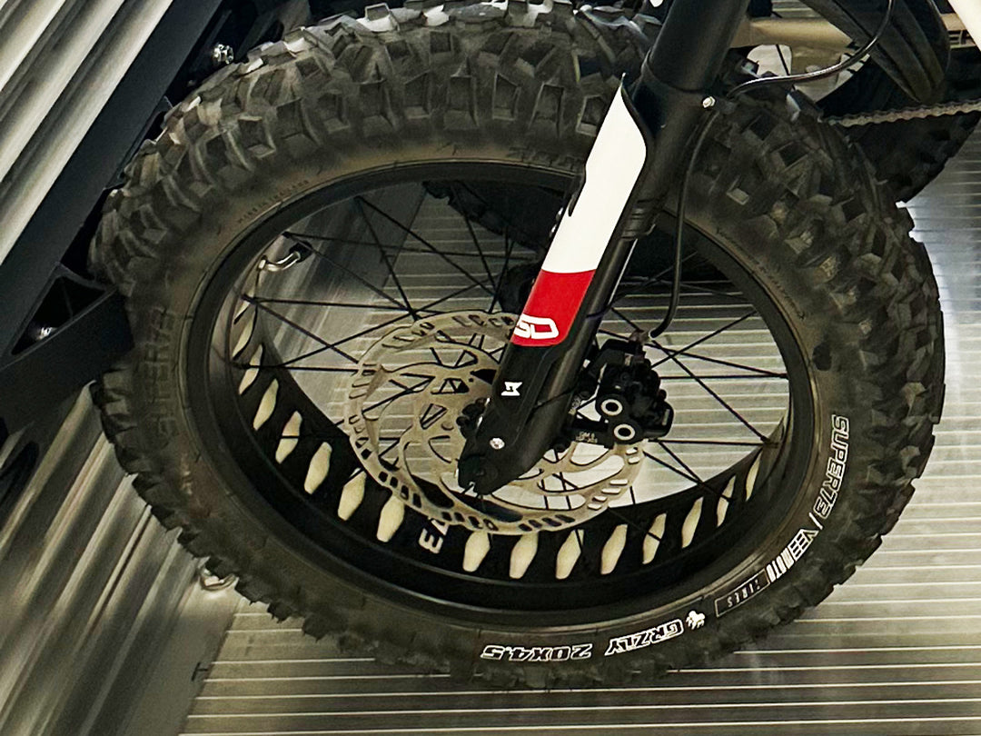 A close-up of the front wheel of a Super 73 ebike stabilized in a utility trailer with the Hybrid Moto Rack system.