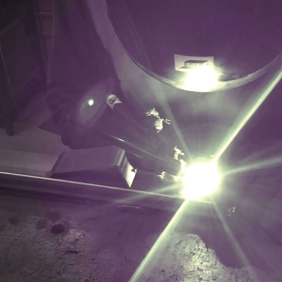 A close-up of a man welding a CCR Sport Bed Buddy Moto Rack.