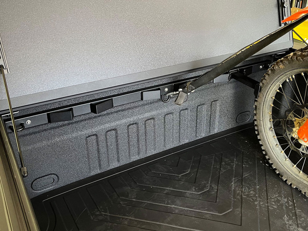 A Bed Buddy Offset Wheel Chock shown with a dirt bike being set back for proper clearance from a BakFlip bed cover.