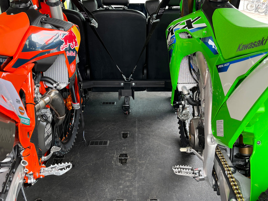 Two off-road motorcycles secured behind passenger seating inside a Ford Transit van using the CCR Sport Hybrid Moto Rack System.