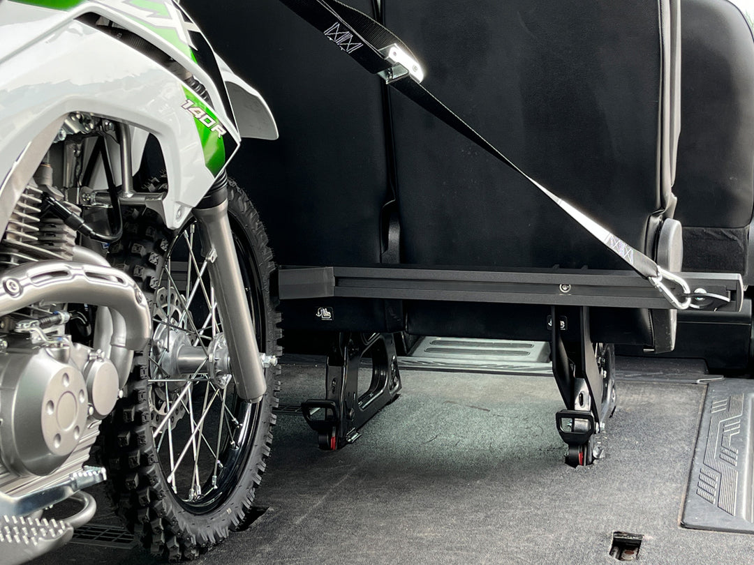 Off-road motorcycle secured behind passenger seating inside a Ford Transit van using the CCR Sport Hybrid Moto Rack System.