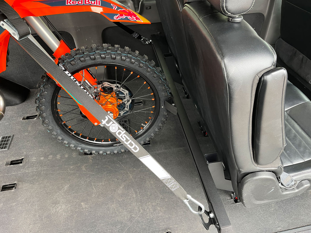 Off-road motorcycle secured behind passenger seating inside a Ford Transit van using the CCR Sport Hybrid Moto Rack System.