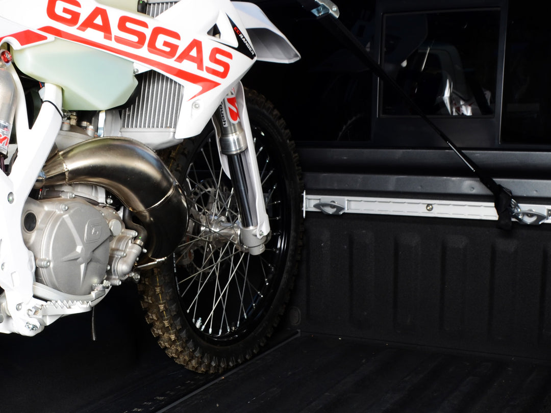 A Nissan truck equipped with the Utili-track cargo rail system and a Gas Gas motorcycle tie down with CCR Sport components.