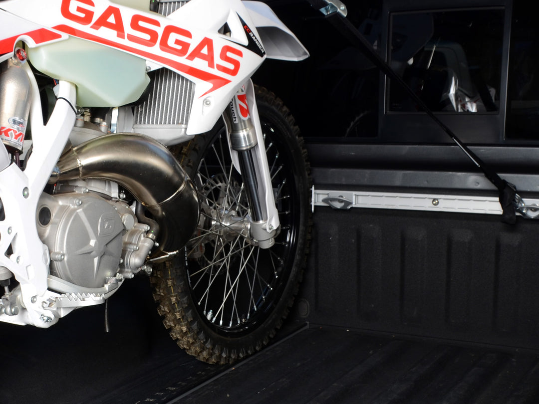 A dirt bike supported by the Utili-track cargo rail system using CCR Sport components like heel chocks and tie-down anchors.